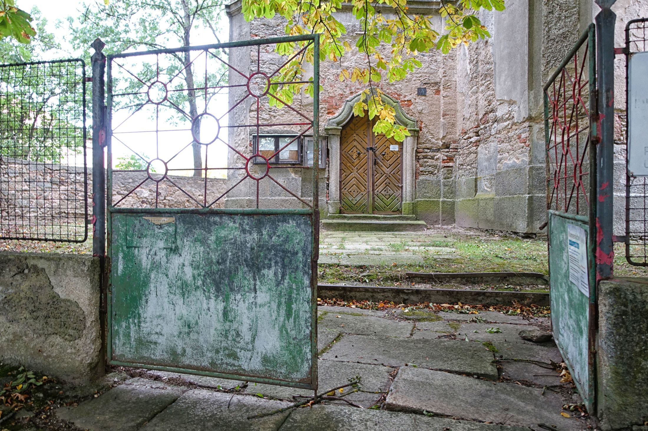 Vstupní zrezivělá branka do areálu kostela.